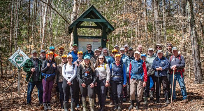 A large group of land stewards gather at the kiosk for a photo.