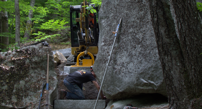 Heavy machine picks up granite step for the trail.