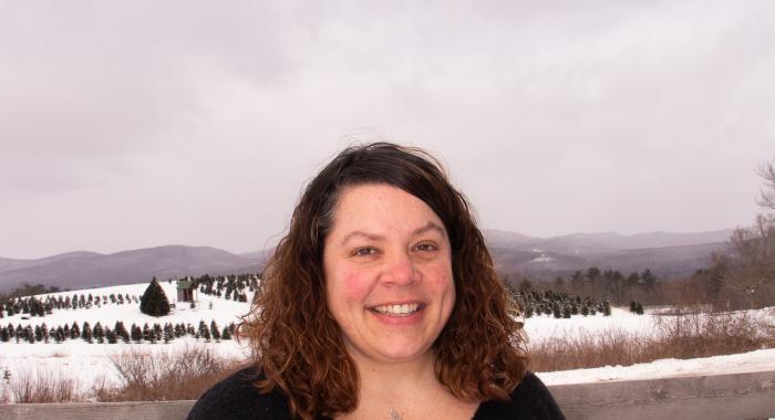 Woman in black sweater in front of snowy fields. 