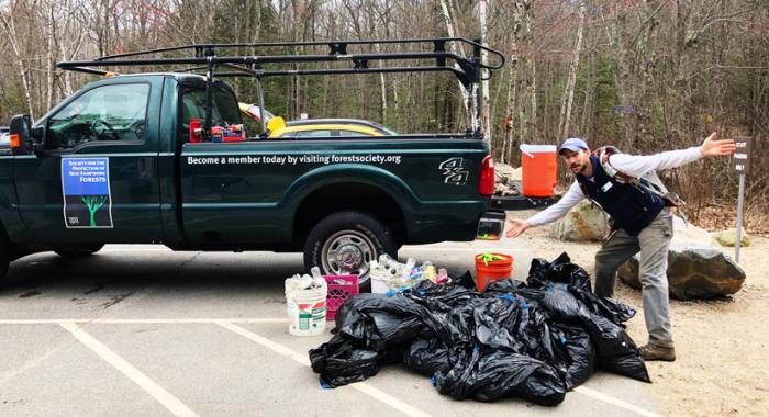 Staff Member standing in front of Forest Society pick up truck with trash found on Mount Major
