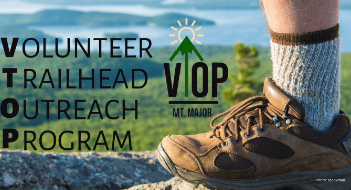 View of the lake from the summit of Mount Major with a hiker's boot and text that reads Volunteer Trailhead Outreach Program.