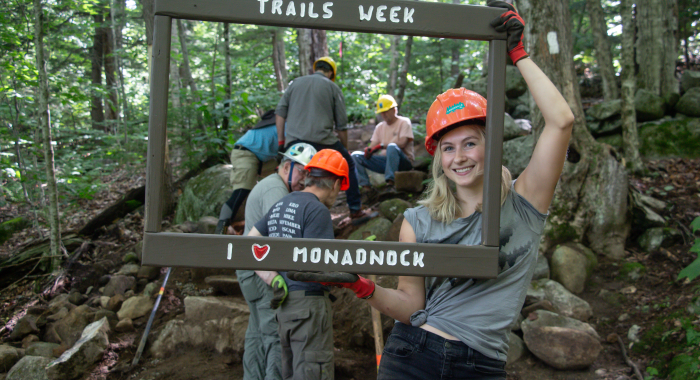 A volunteer poses with a "I love Monadnock" sign frame.