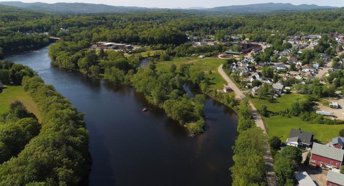 A winding blue river passes the small houses and red barns that make up Franklin, New Hampshire.