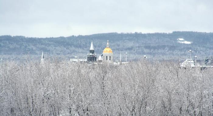 NH State House gold dome surrounded by bare trees with snow on branches