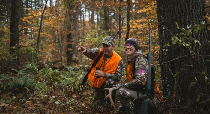 Two hunters in blaze orange clothing in NH autumn woodland scene