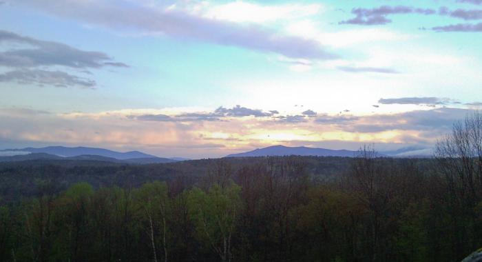 The sun sets over a mountain view from The Rocks.