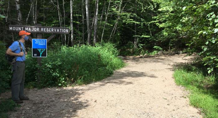 A mask-clad hiker pauses at the trailhead at Mount Major.