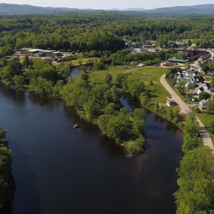 A winding blue river passes the small houses and red barns that make up Franklin, New Hampshire.