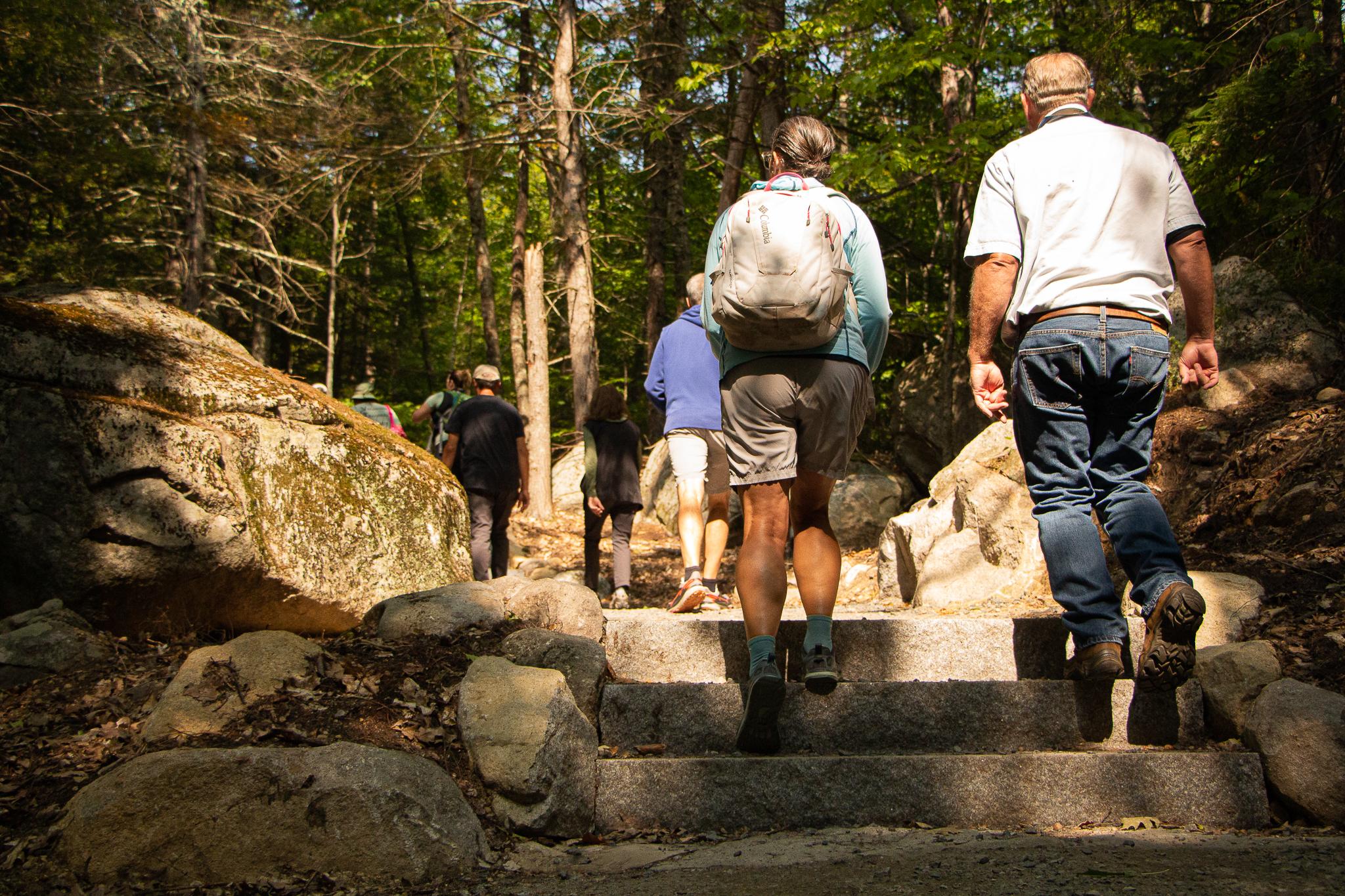 two people wearing hiking clothes climb a short stone staircase 