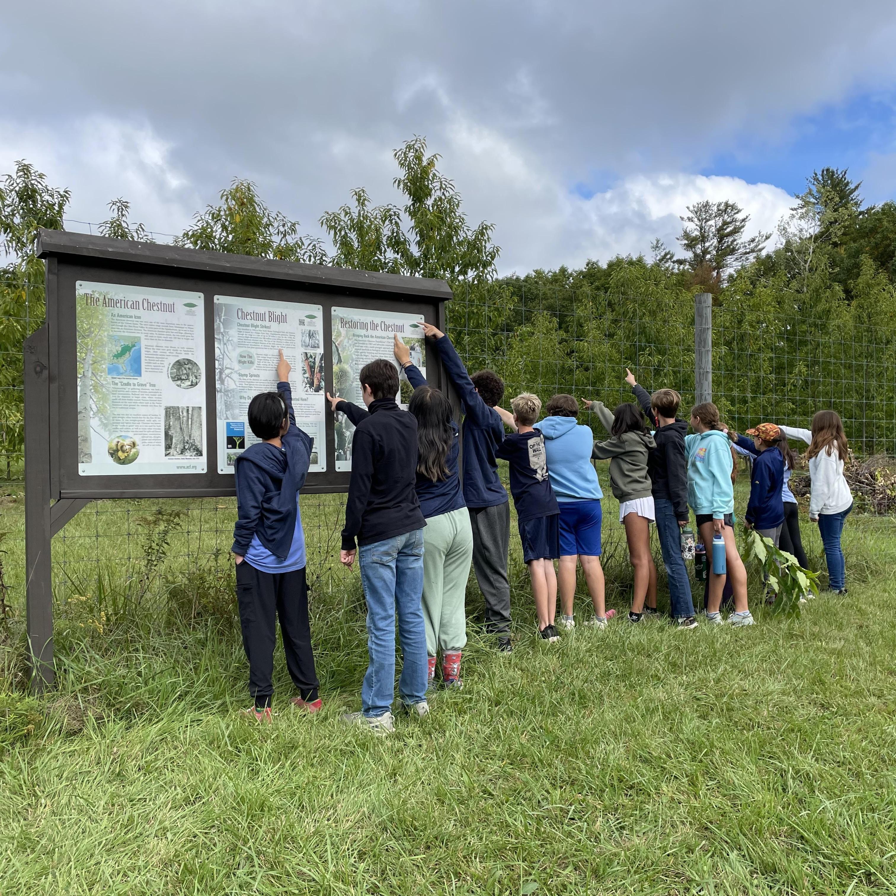 Students point to the sign at Tom Rush Forest.