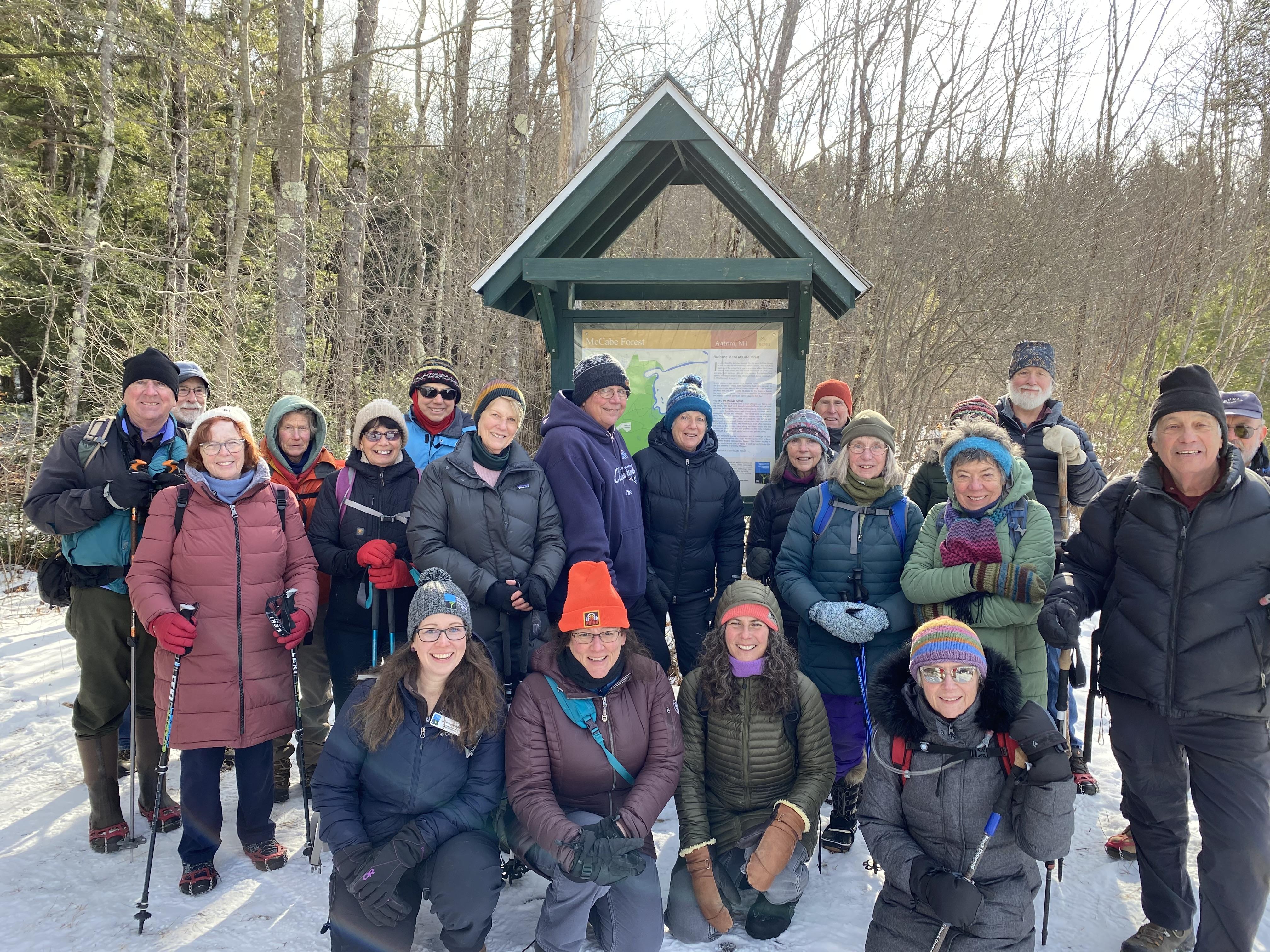 A group of people dressed for winter stand in front of a trail kiosk