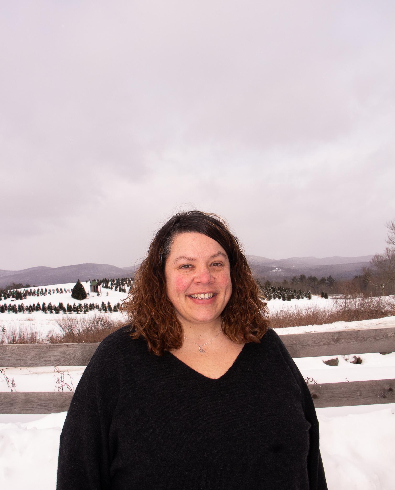 Woman in black sweater in front of snowy fields. 