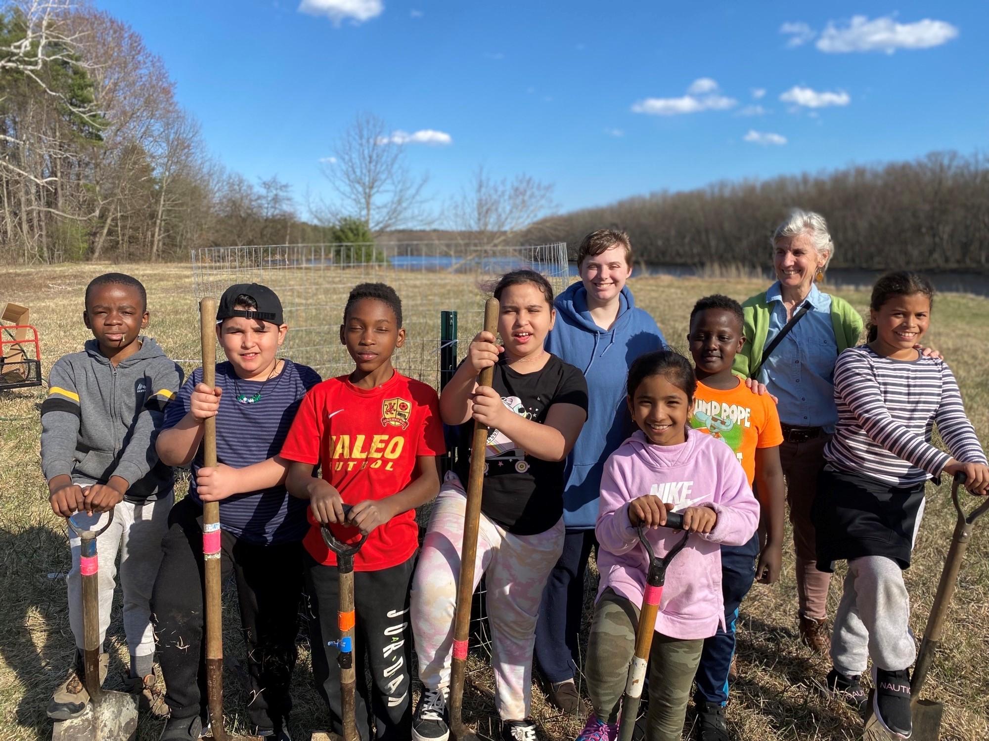 Students pose with shovels after planting trees