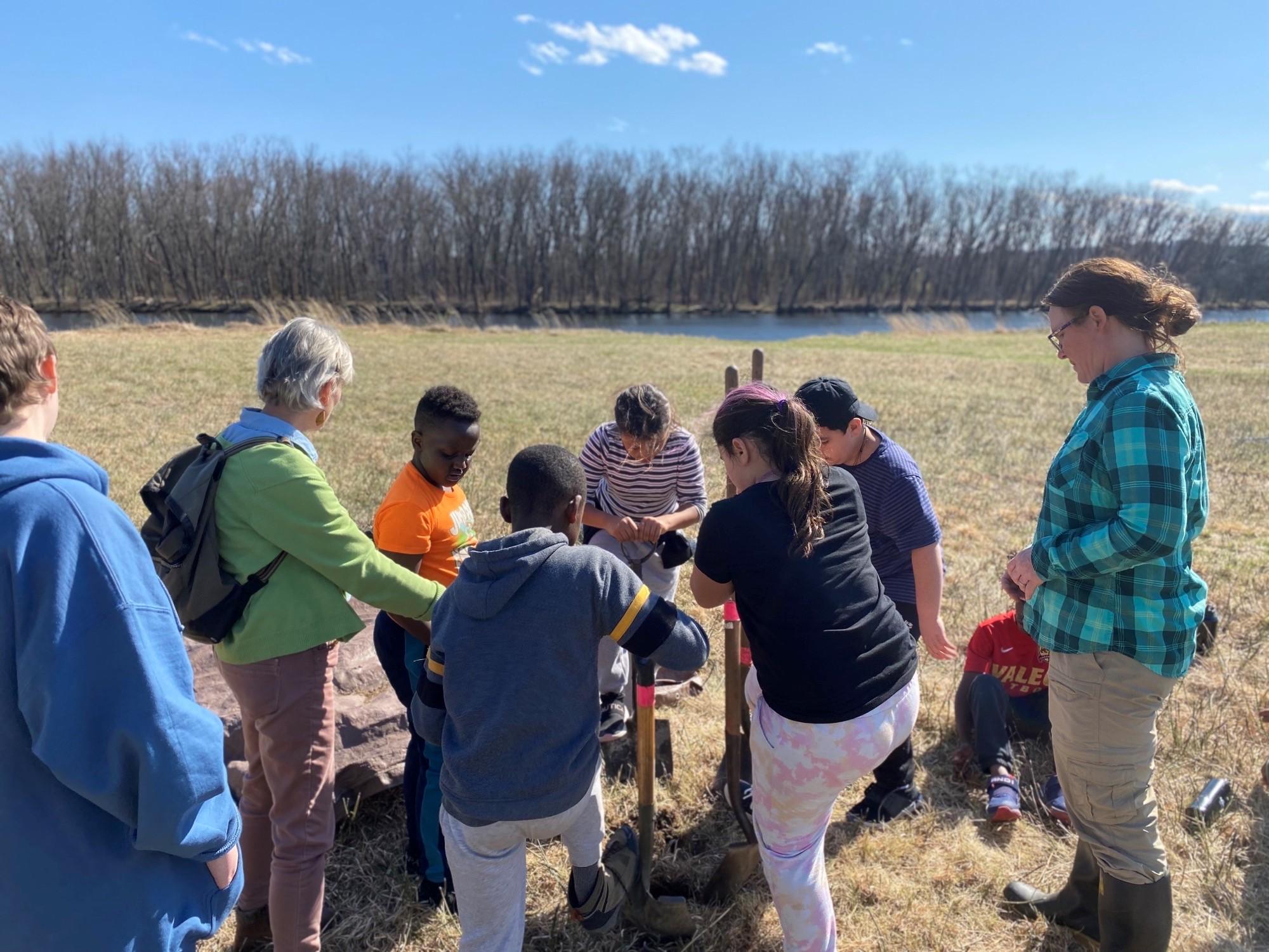 Students work with shovels to begin planting of mulberry trees