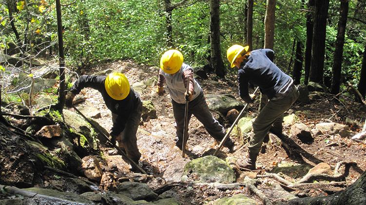 A Student Conservation Association crew moves a stone step into place on Mt. Monadnock.