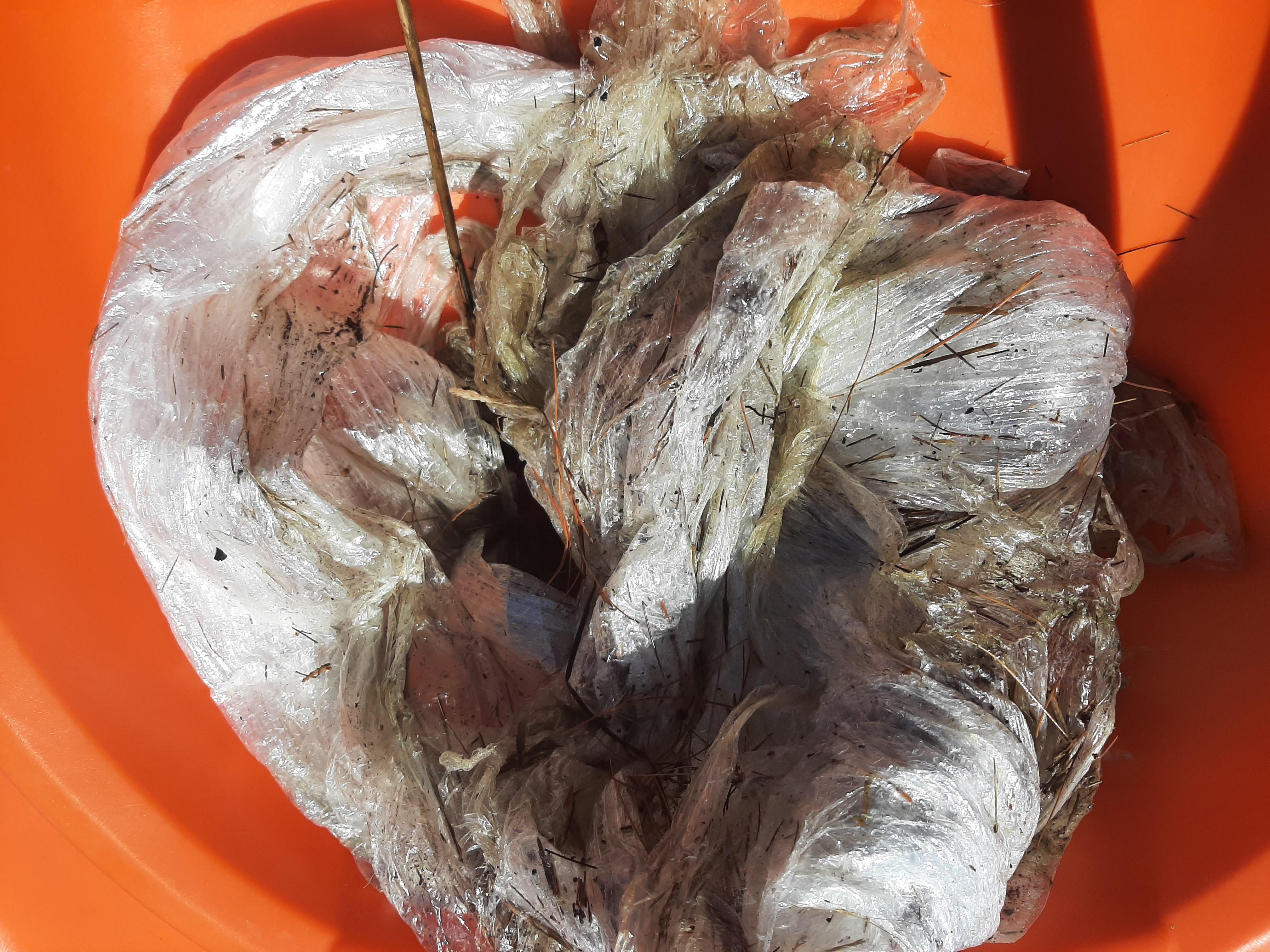 An orange bucket full of littered plastic wrap 