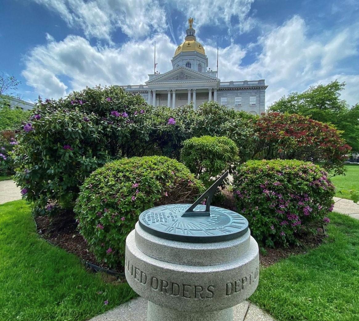 NH State House under a blue sky with wispy clouds