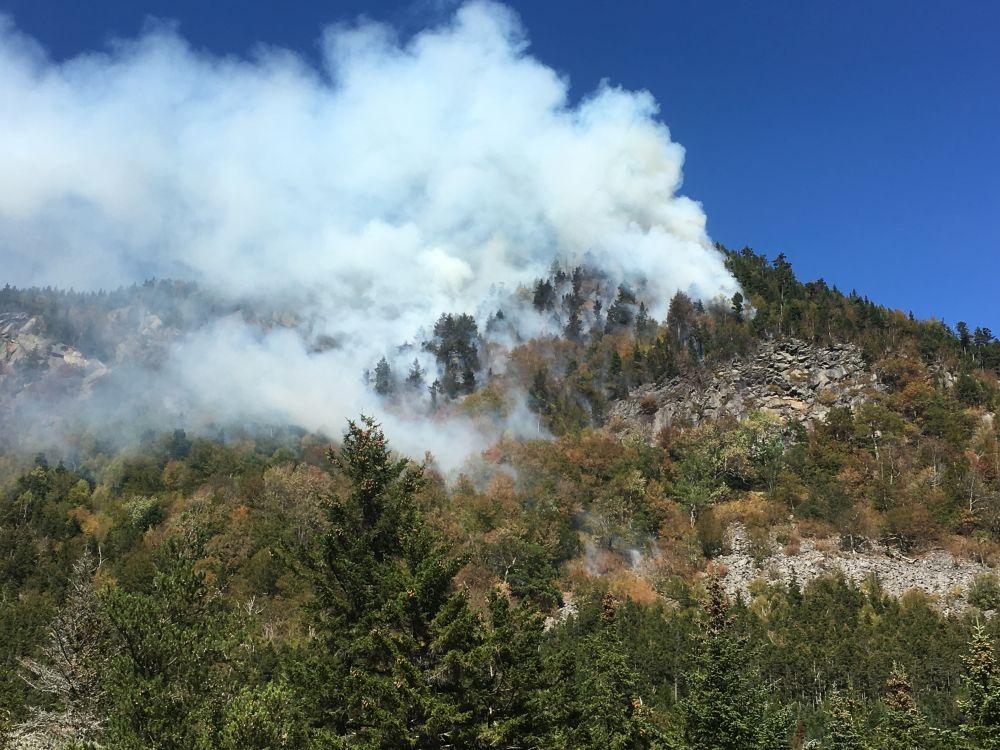 Smoke from a wildfire billowing from a cliff.