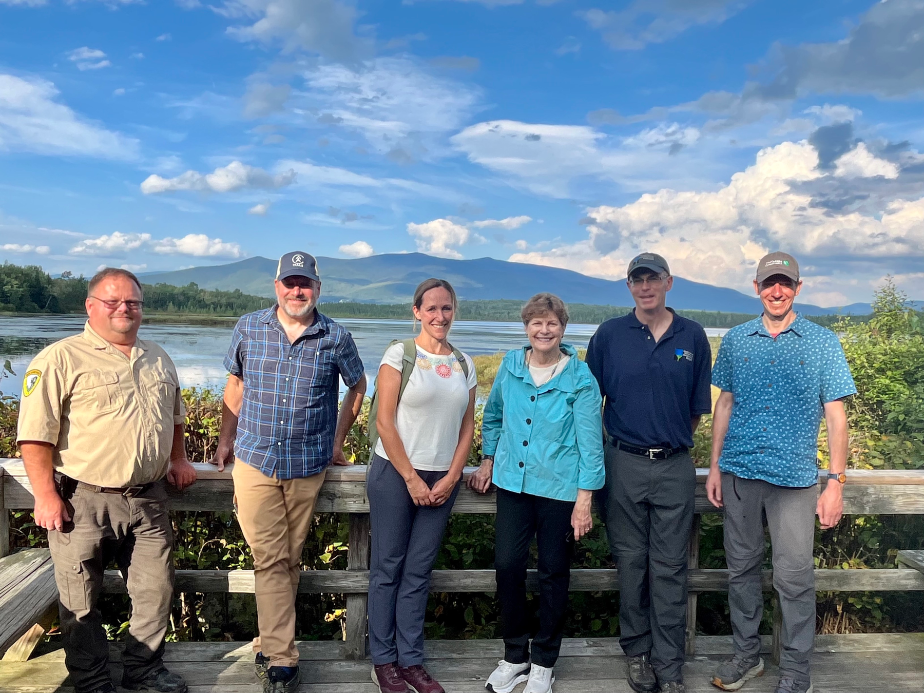 Sen Shaheen and the conservation staff pose in front of Cherry Pond in Whitefield.