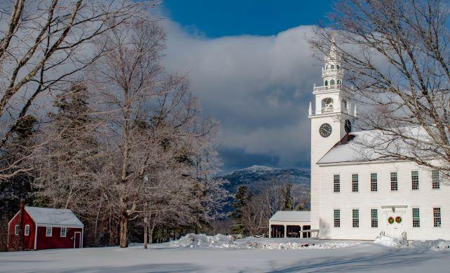 A spectacular view of Mount Monadnock is seen from in between a church and barn.