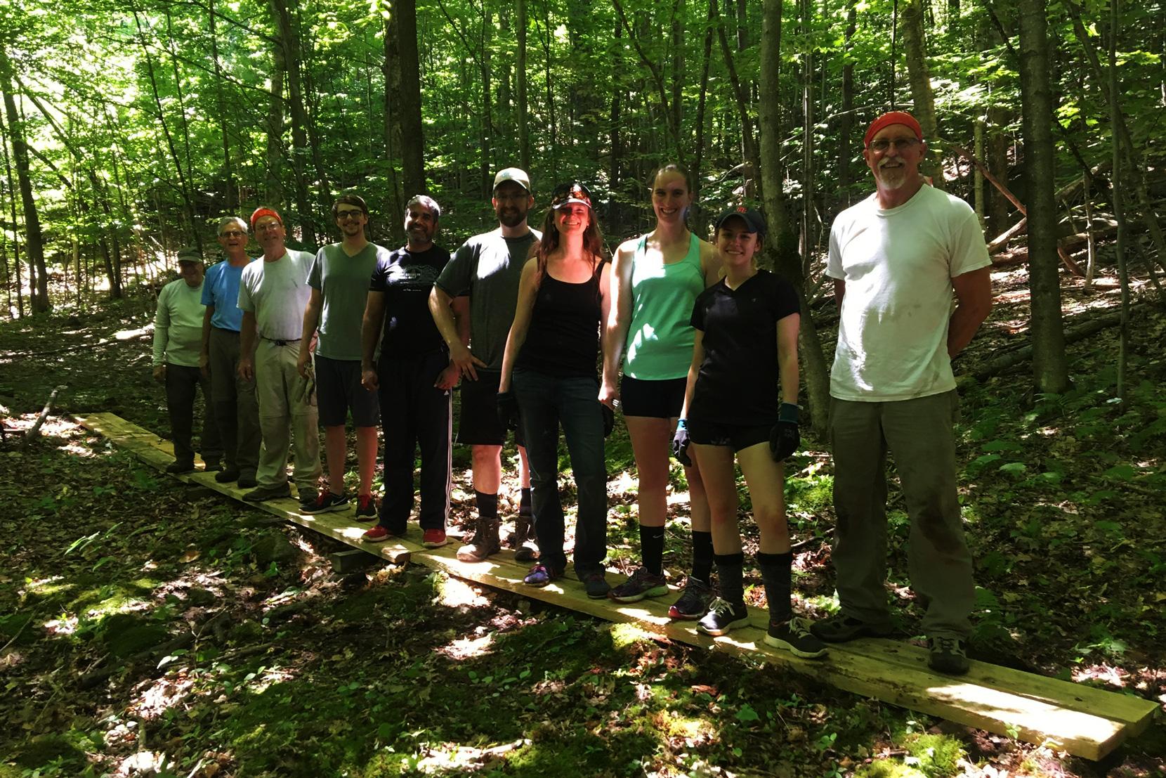 Volunteers showcase a completed bog bridge on the XC Ski Trail