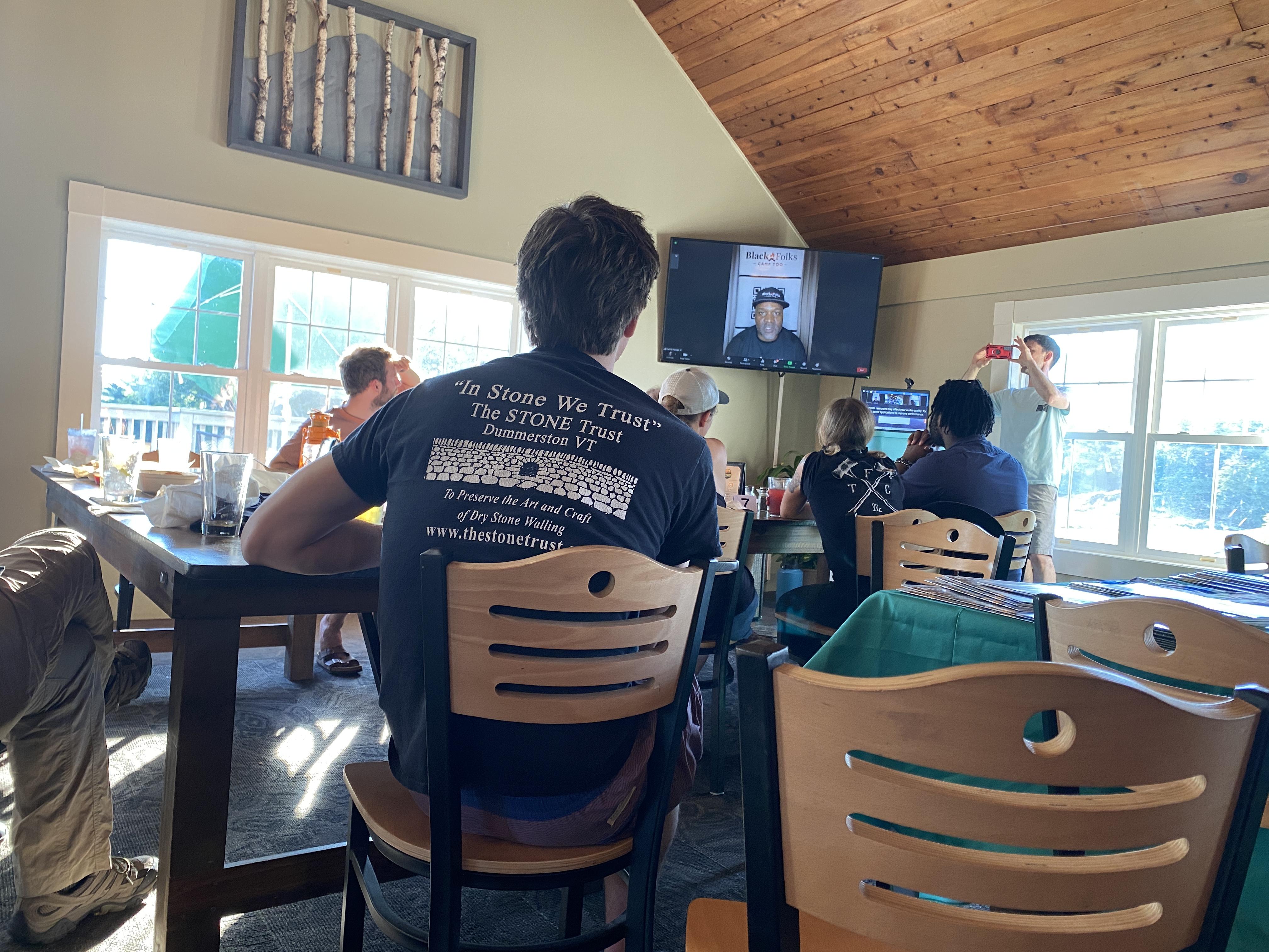 People gather around a table with a screen for the program.