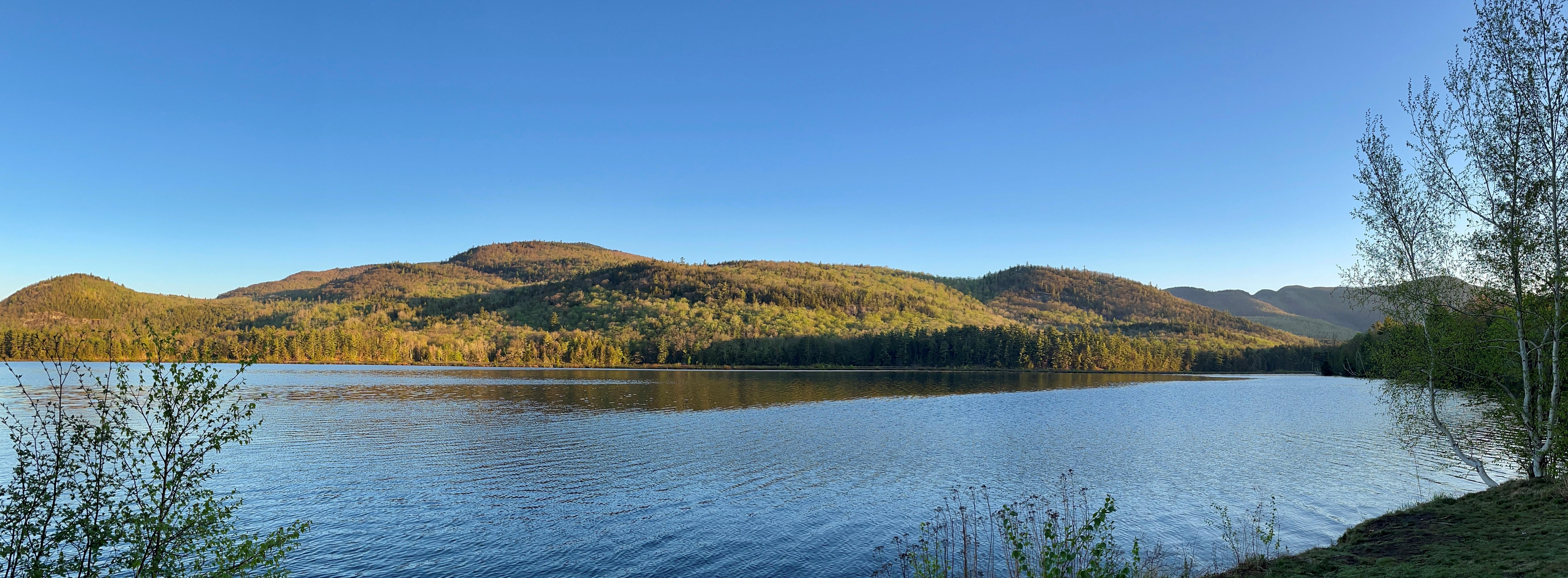 The Mahoosuc Highlands pictured in summer with a lake in the forground.