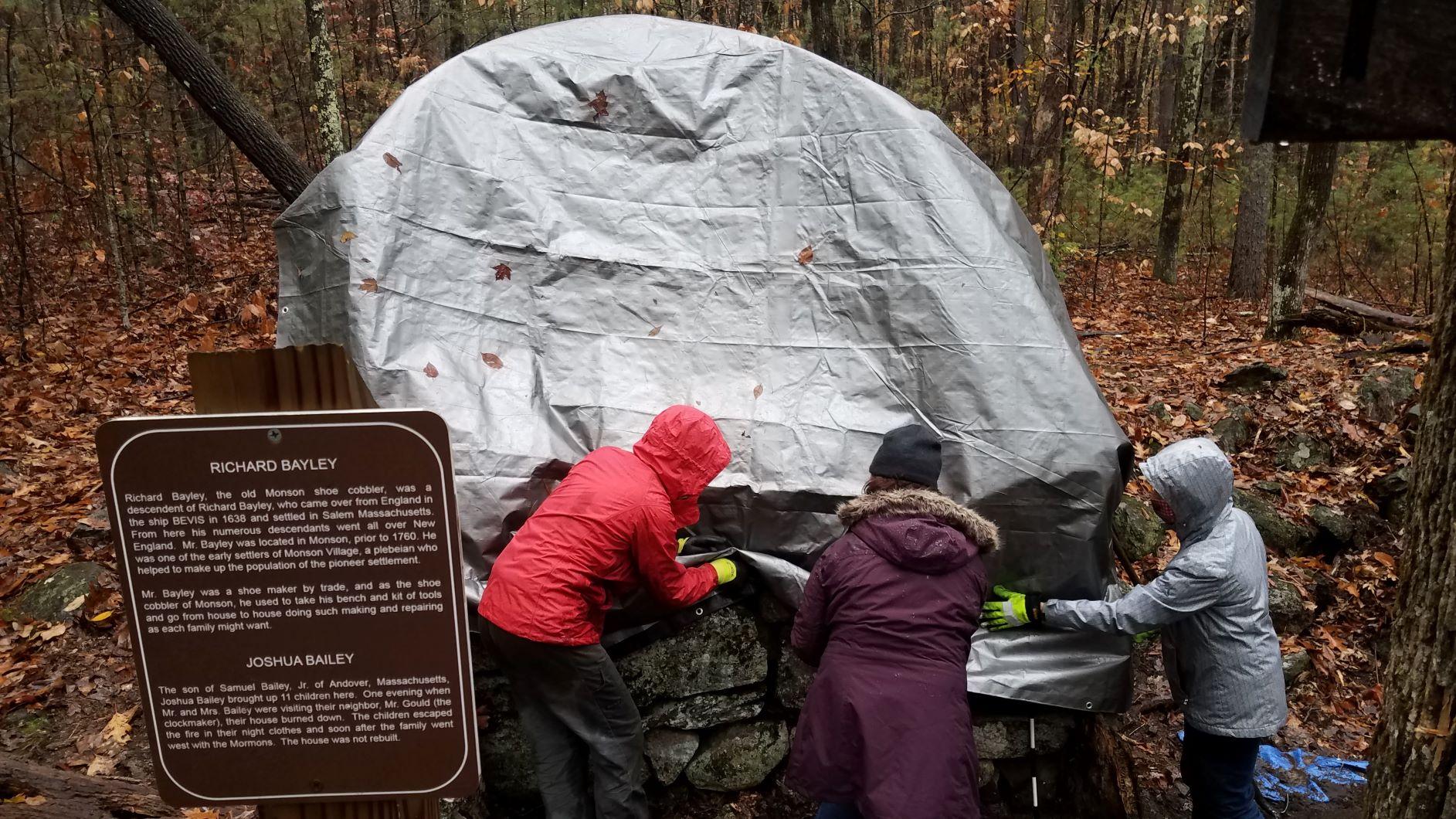 A gray tarp covers a rock foundation at Monson Village.