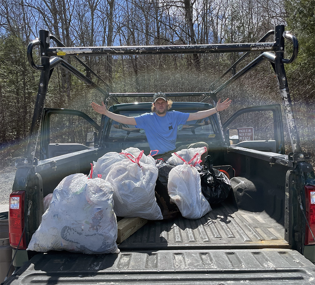 Cameron Larnerd poses with trash in the back of a pickup truck.