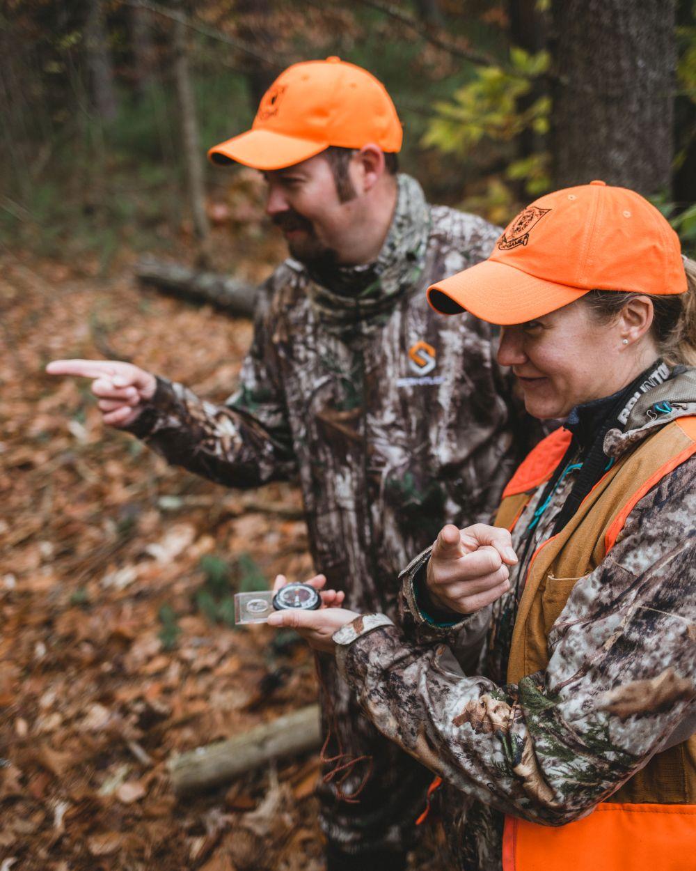 Hunters in camoflage and blaze orange practice map and compass skills