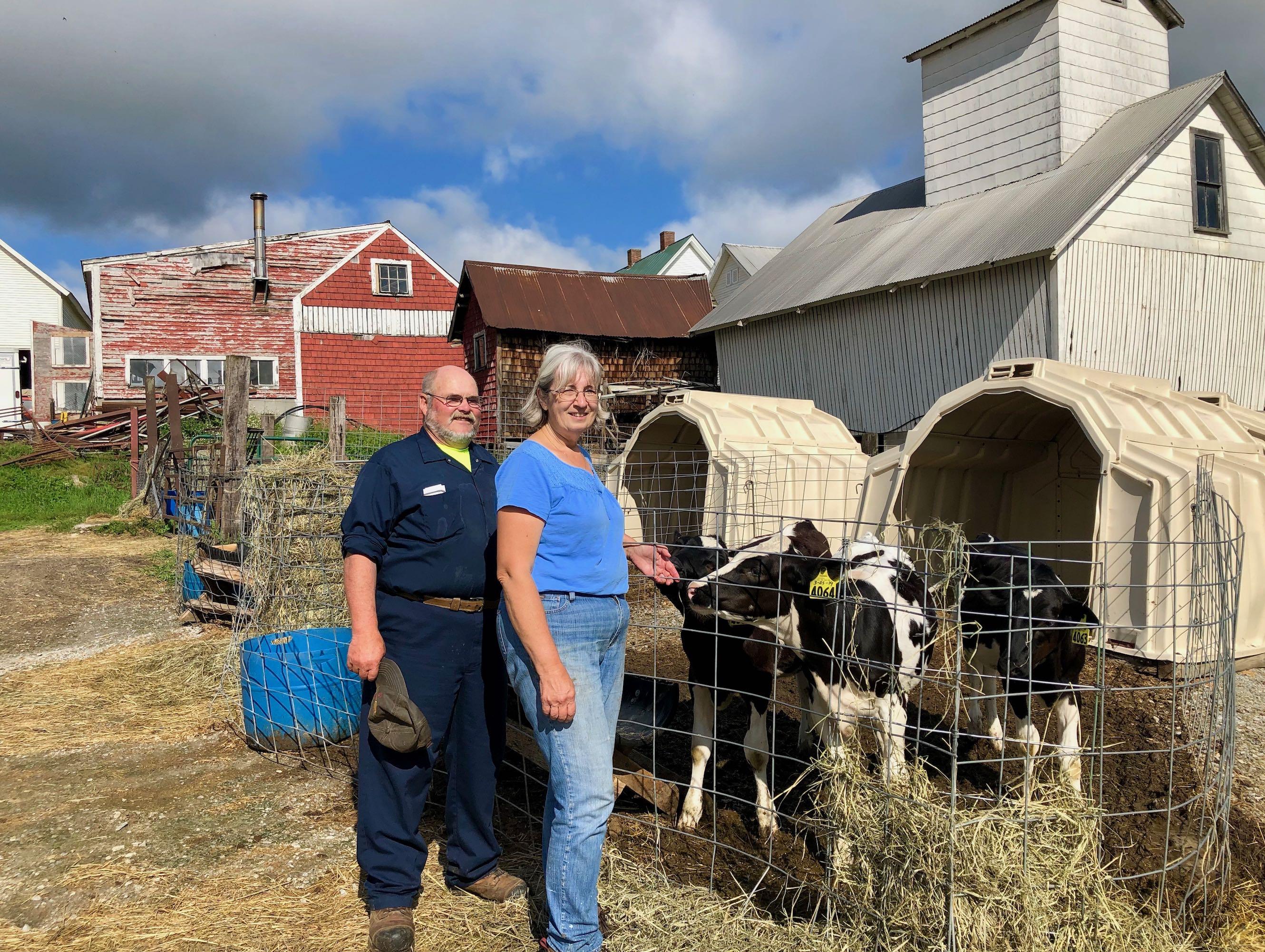 The Morrills stand next to a cow in front of a red barn.