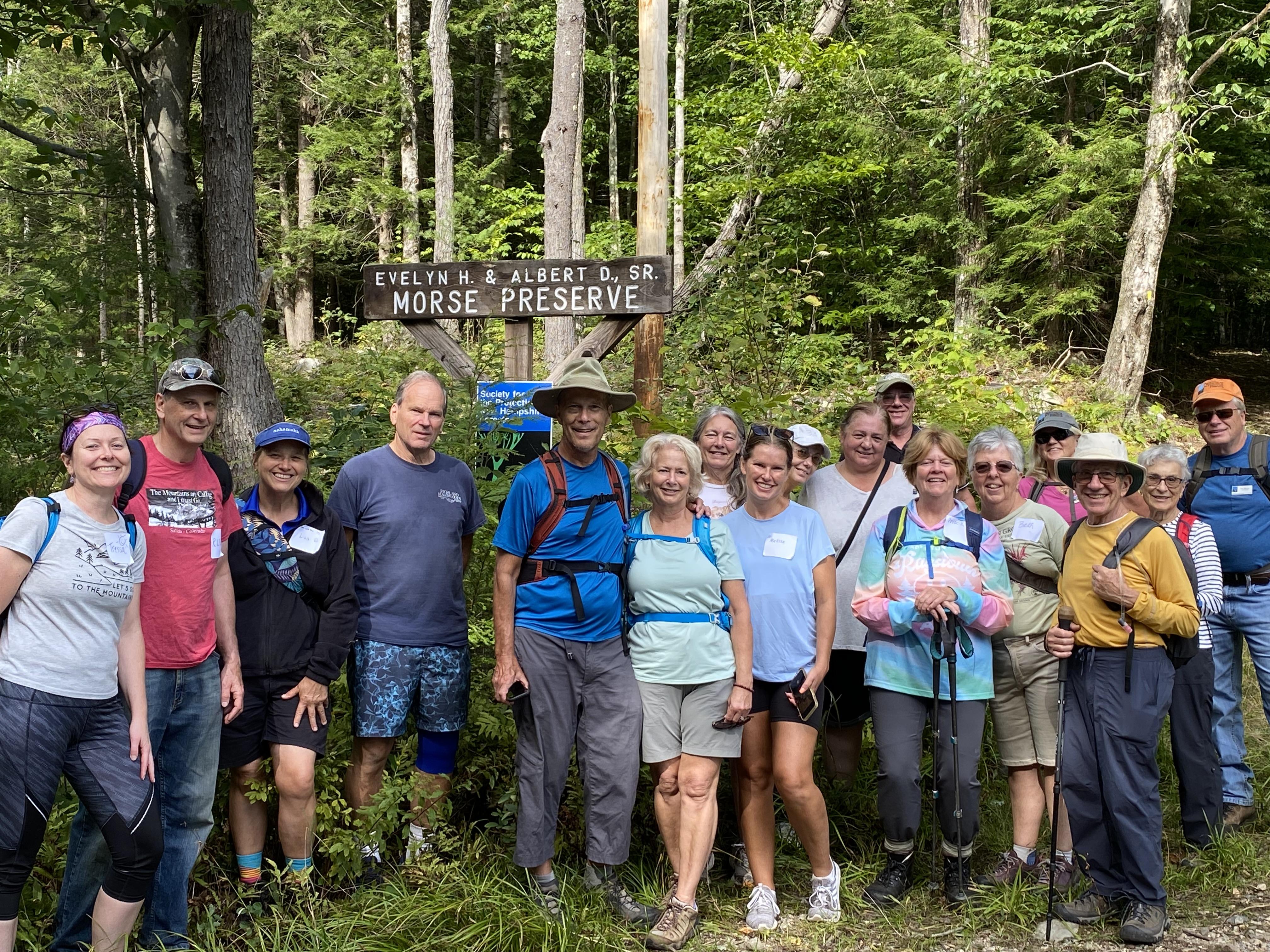 hiking group stand in front of roadside property sign 