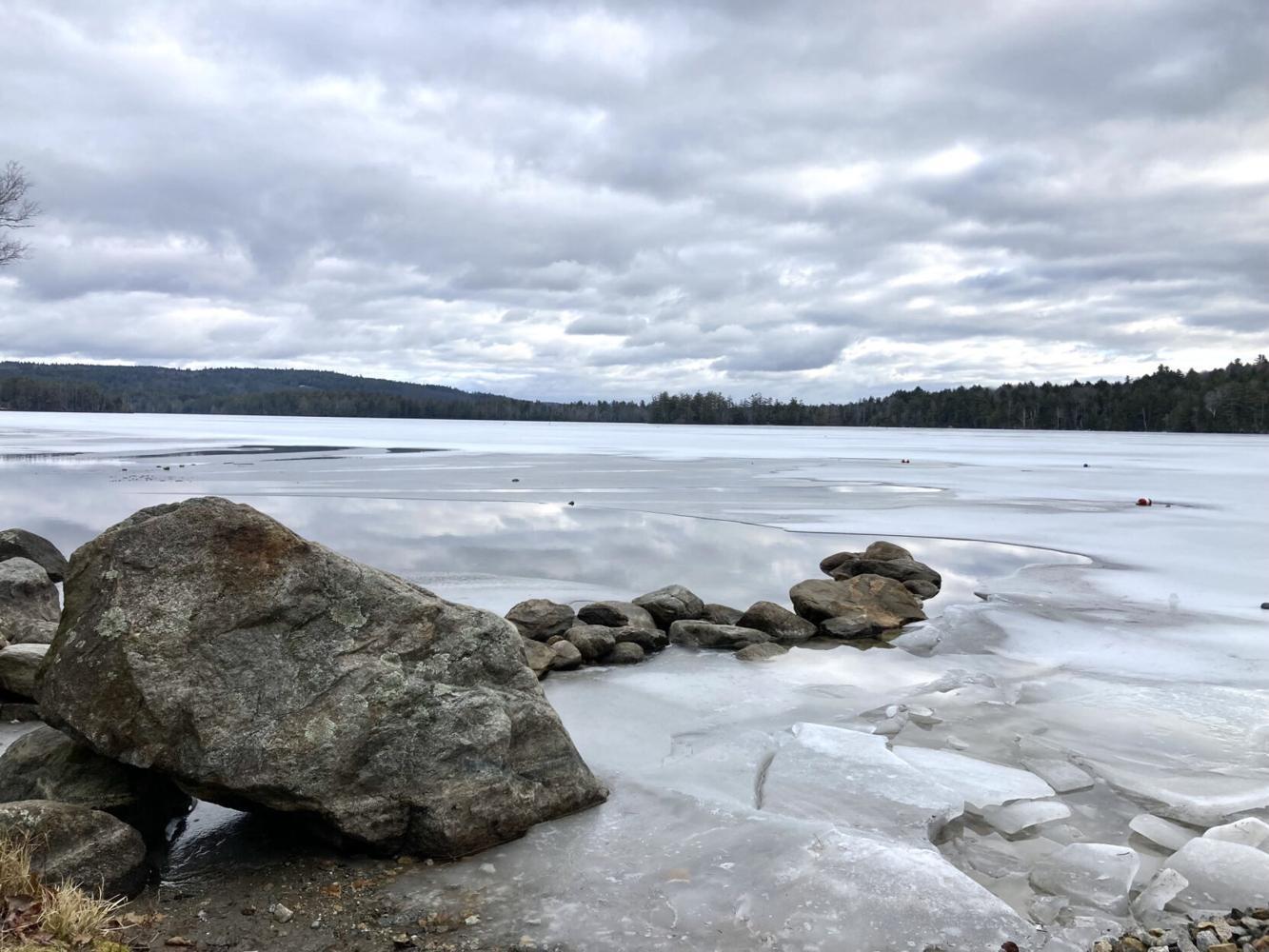 A line of rocks stretches into a frozen winter lake