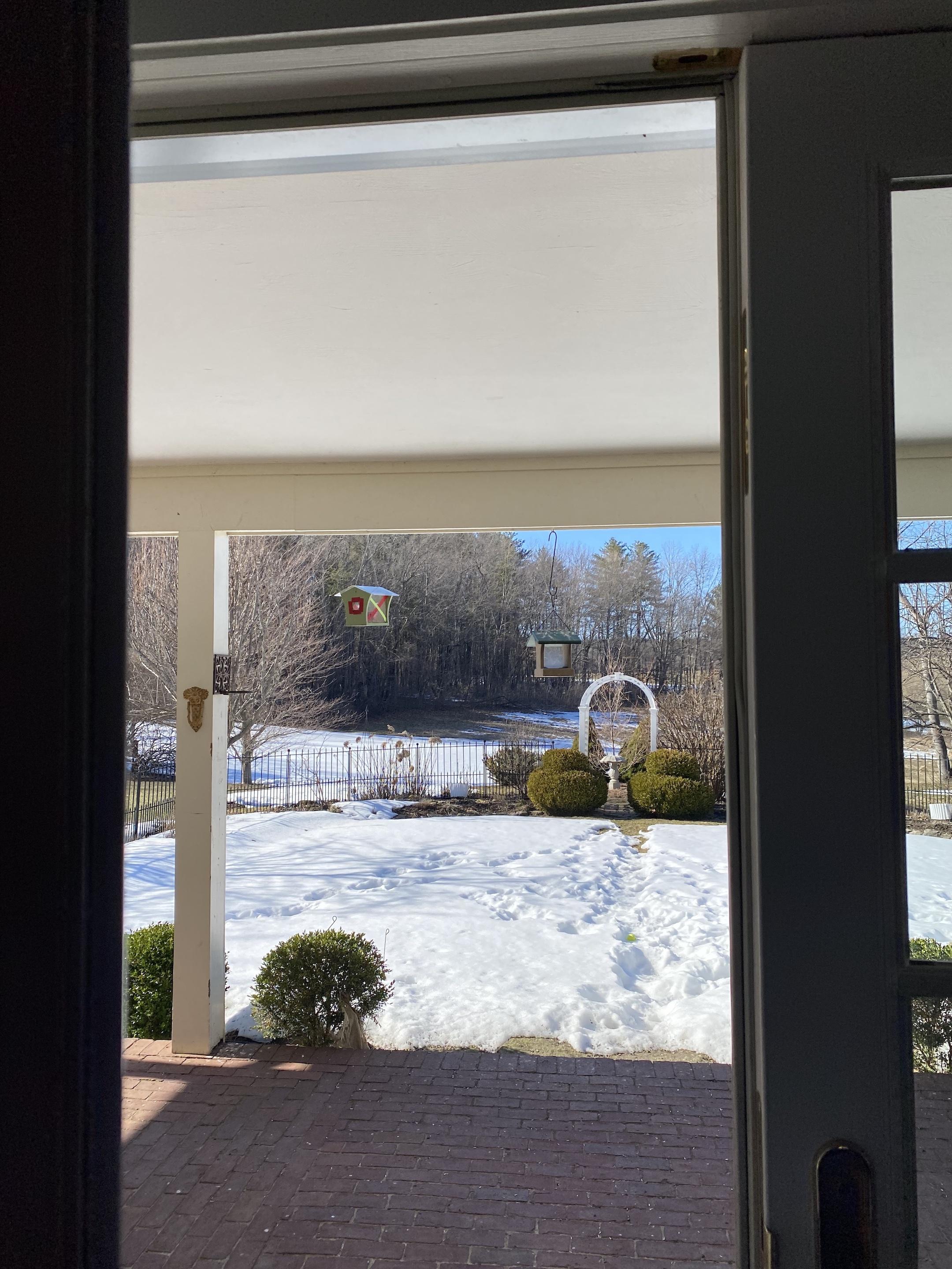 Looking out to a snowy field from an open glass door