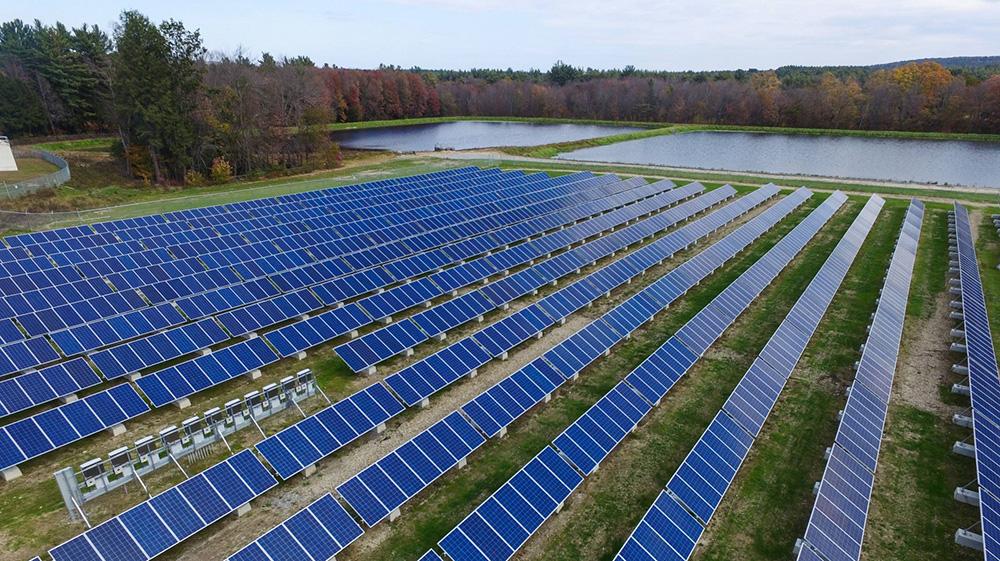 three large fields of solar panels surrounded by forest