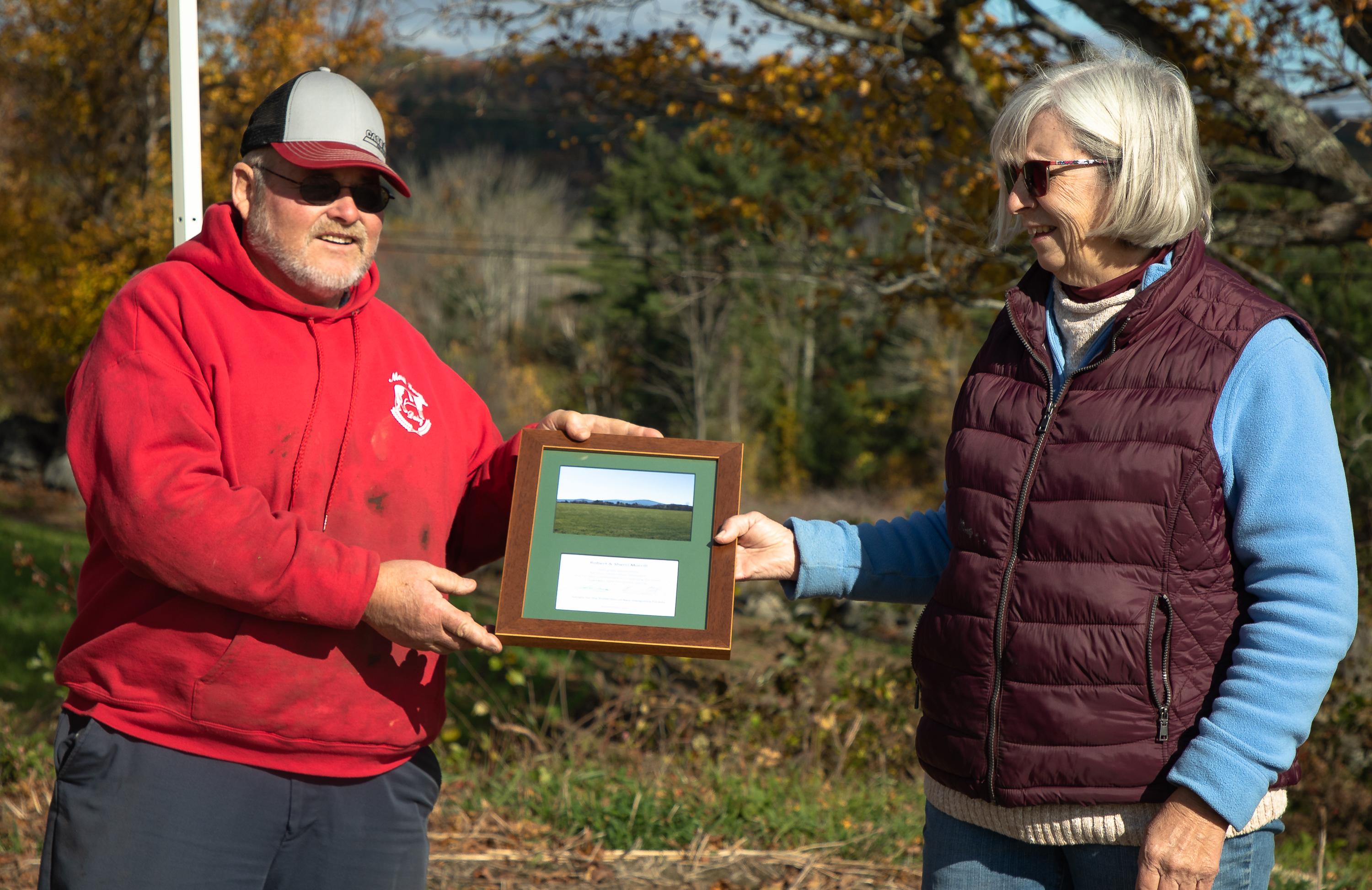 Robert and Sherri Morrill hold a plaque between them during the closing ceremony at the farm.