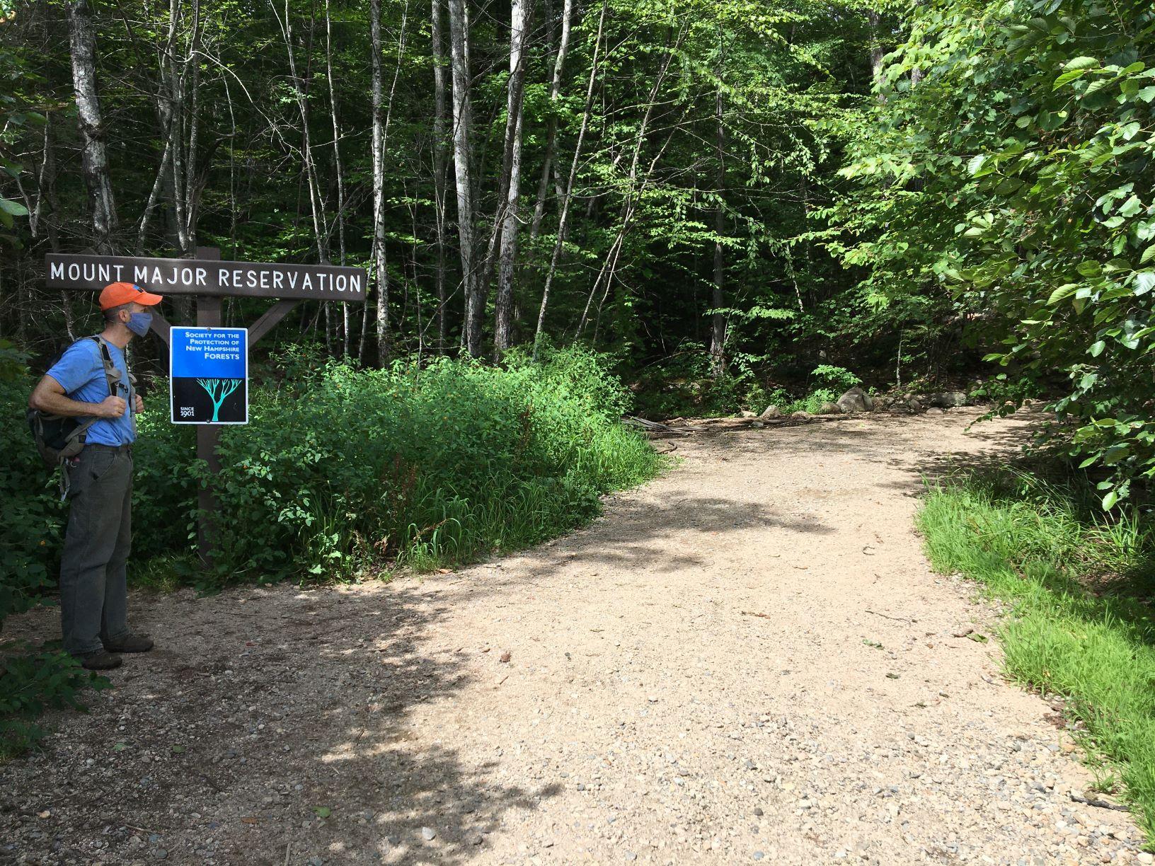 A mask-clad hiker pauses at the trailhead at Mount Major.