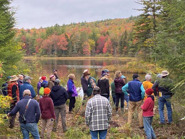 colorful hikers, fall foliage along shore of Morrill Marsh pond, Wilmot