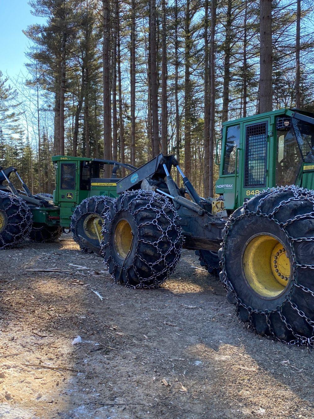 Green and yellow John Deere grapple skidders on landing