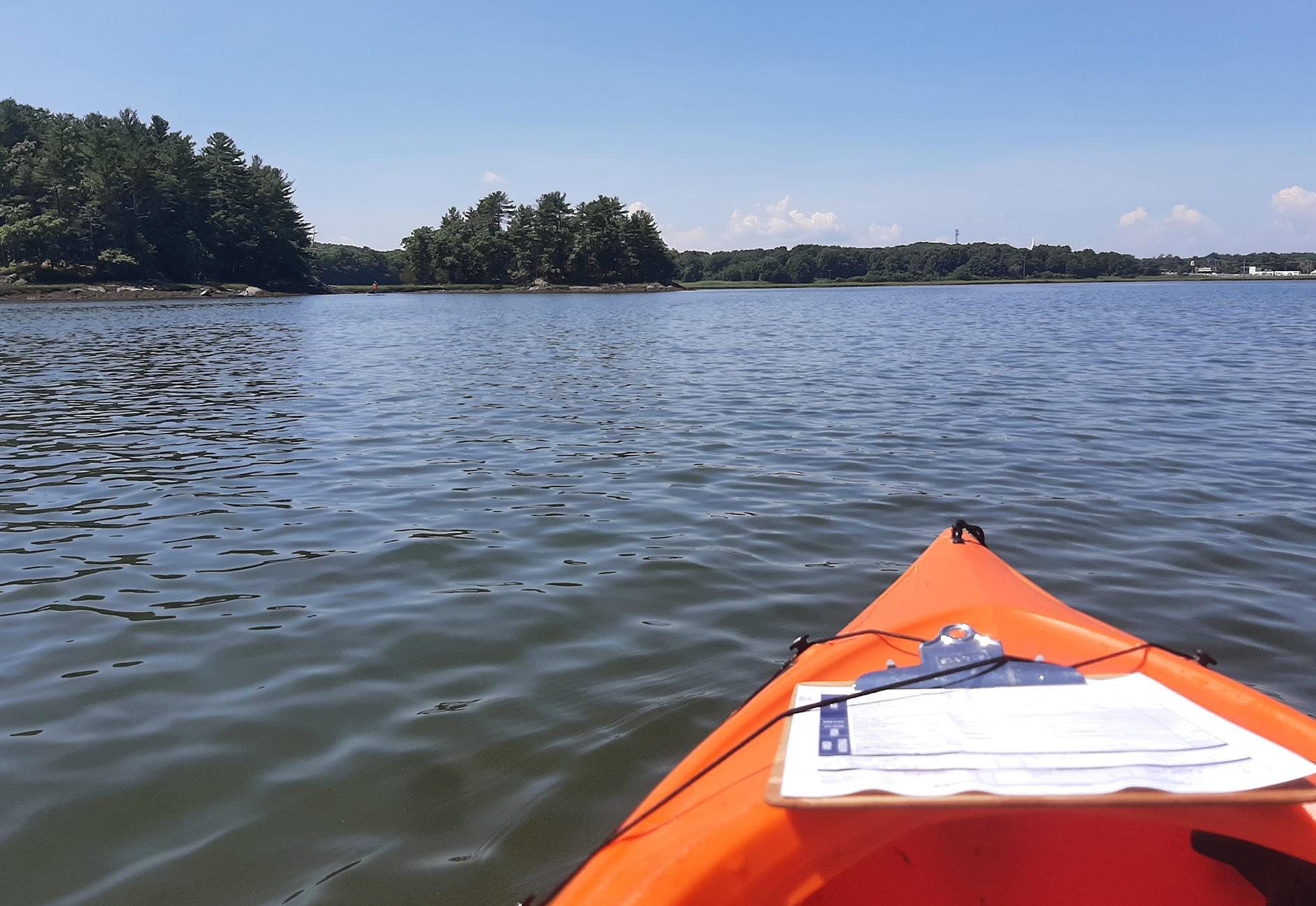 Paddler's view of an orange kayak with clipboard in the ocean