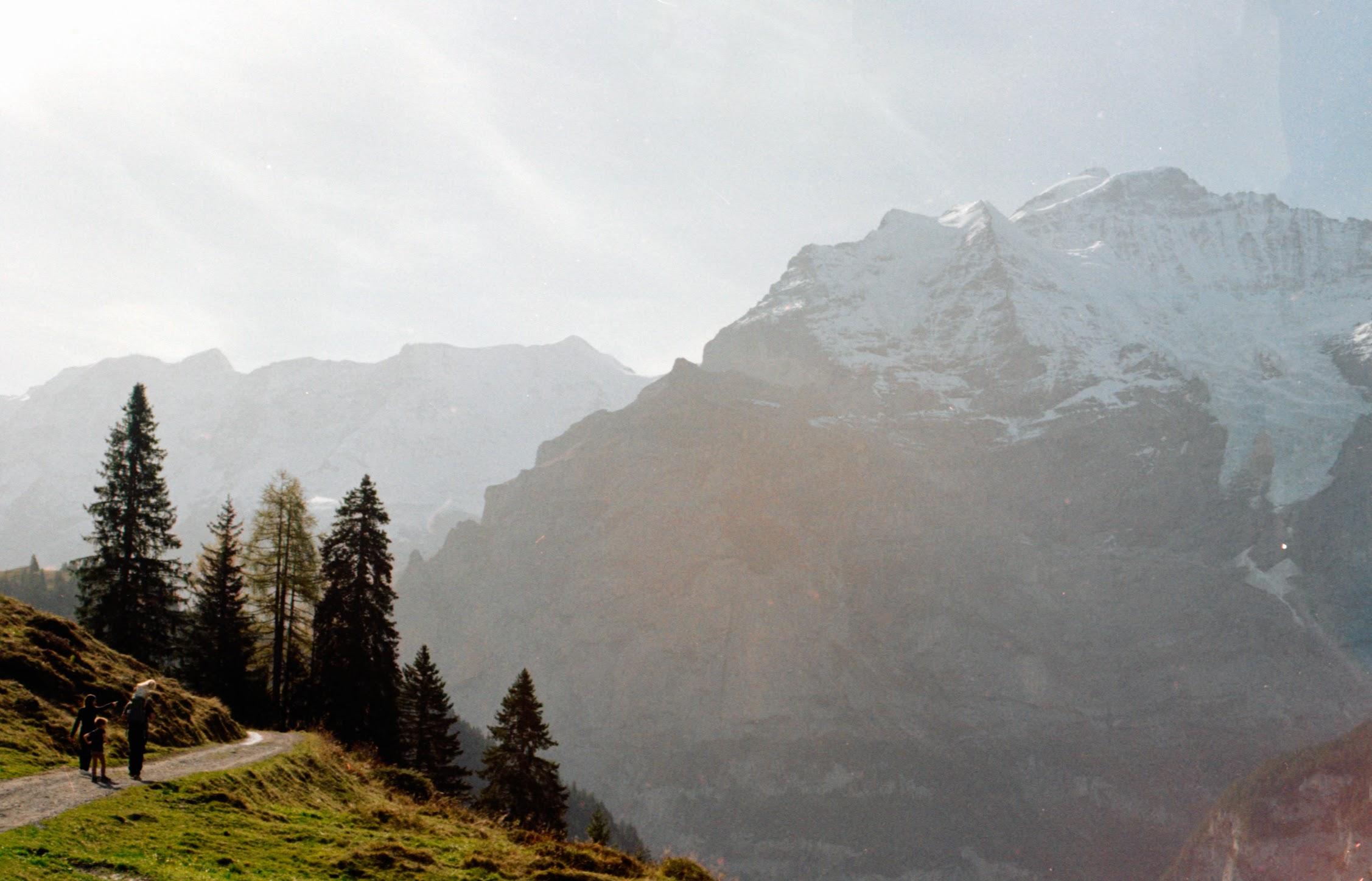 Mountains overlooking a trail where people are walking 