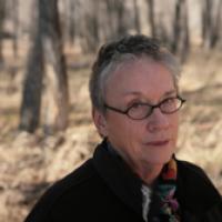 Annie Proulx poses outside in front of bare trees.