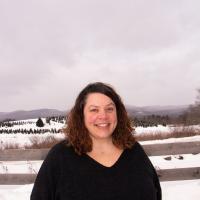 Woman in black sweater in front of snowy fields. 