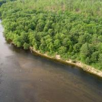 A bend in the Merrimack river lined with green trees from Stillhouse Forest.