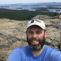 Derek Colquhoun poses on the summit of Mount Major with the lake behind him.