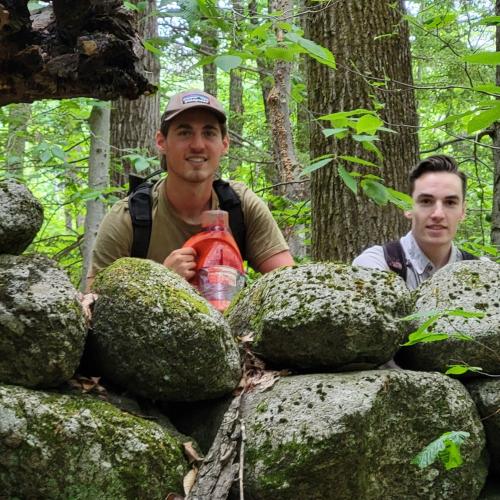 Matt and Donovan pose outside behind a rock wall.