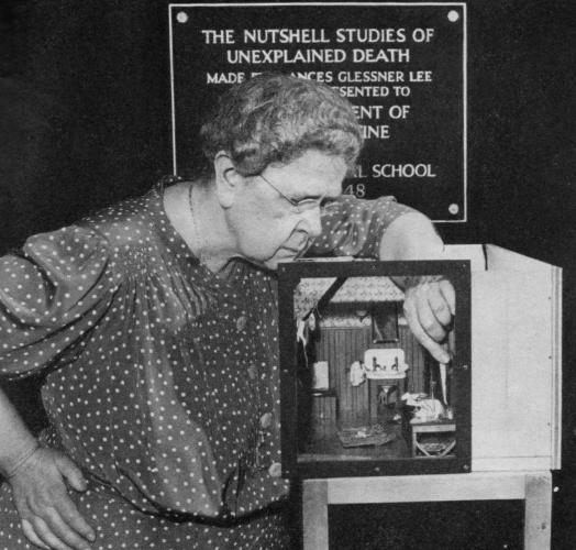 Frances Glessner Lee is shown in black and white as she uses tweezers on her diorama.