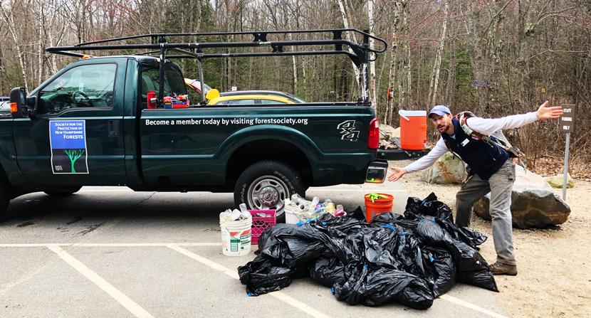 Staff Member standing in front of Forest Society pick up truck with trash found on Mount Major