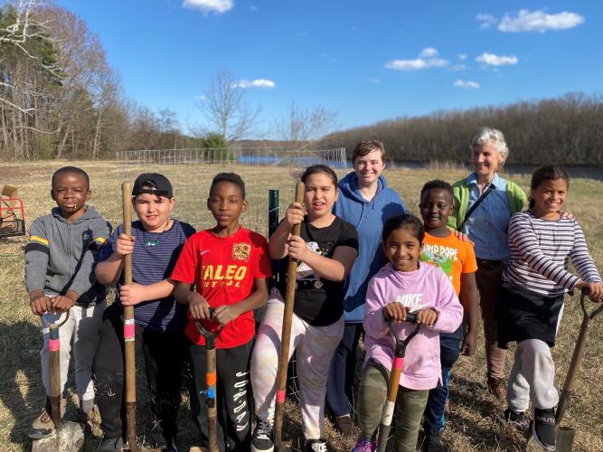 Students pose with shovels after planting trees