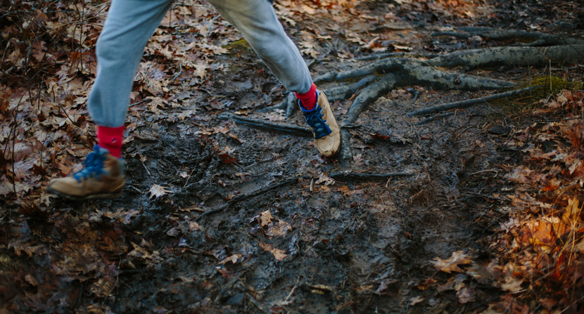 Boy hiking and running along muddy trail
